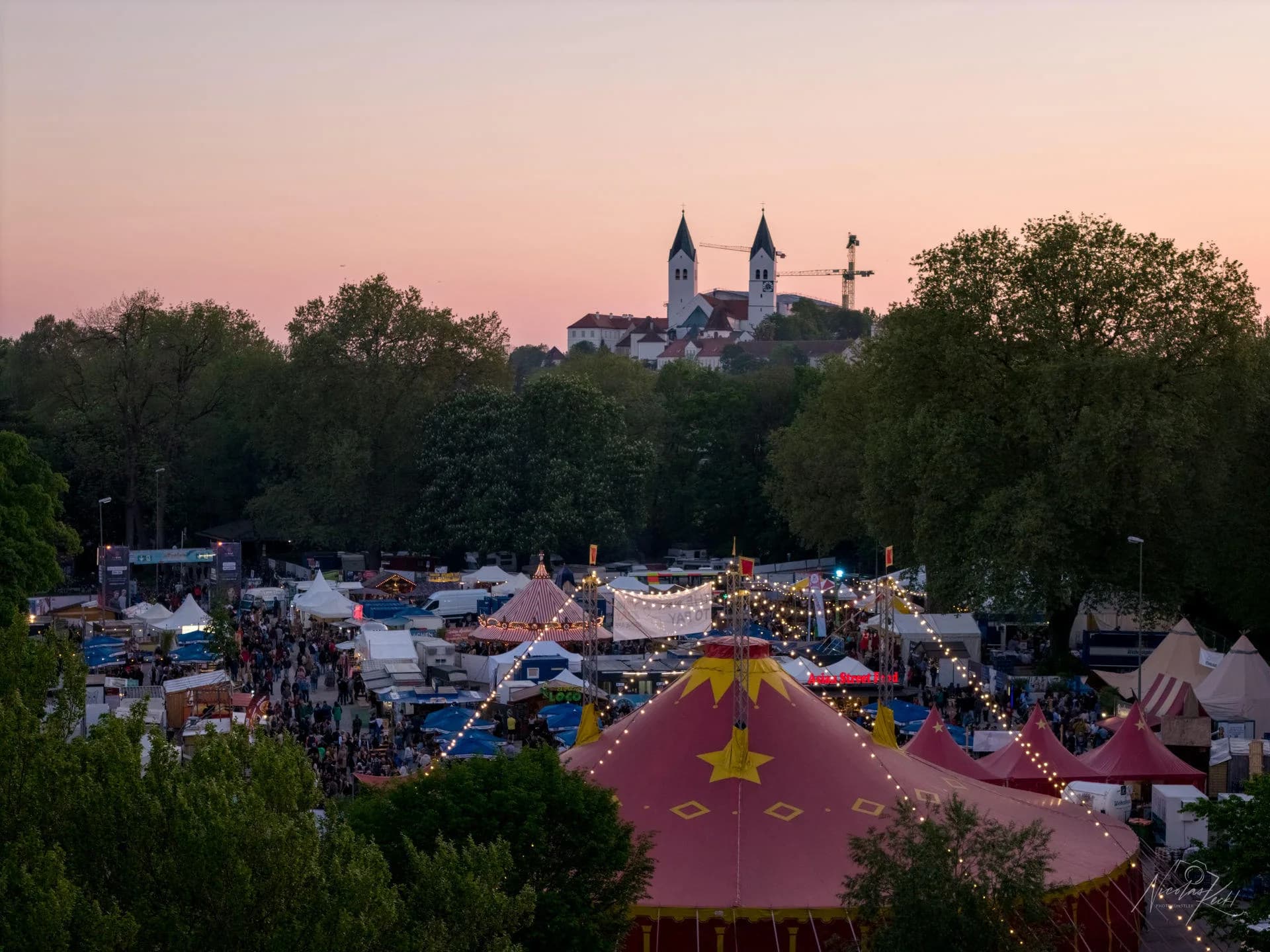 Aerial view of the Uferlos festival grounds glowing in warm sunset light.
