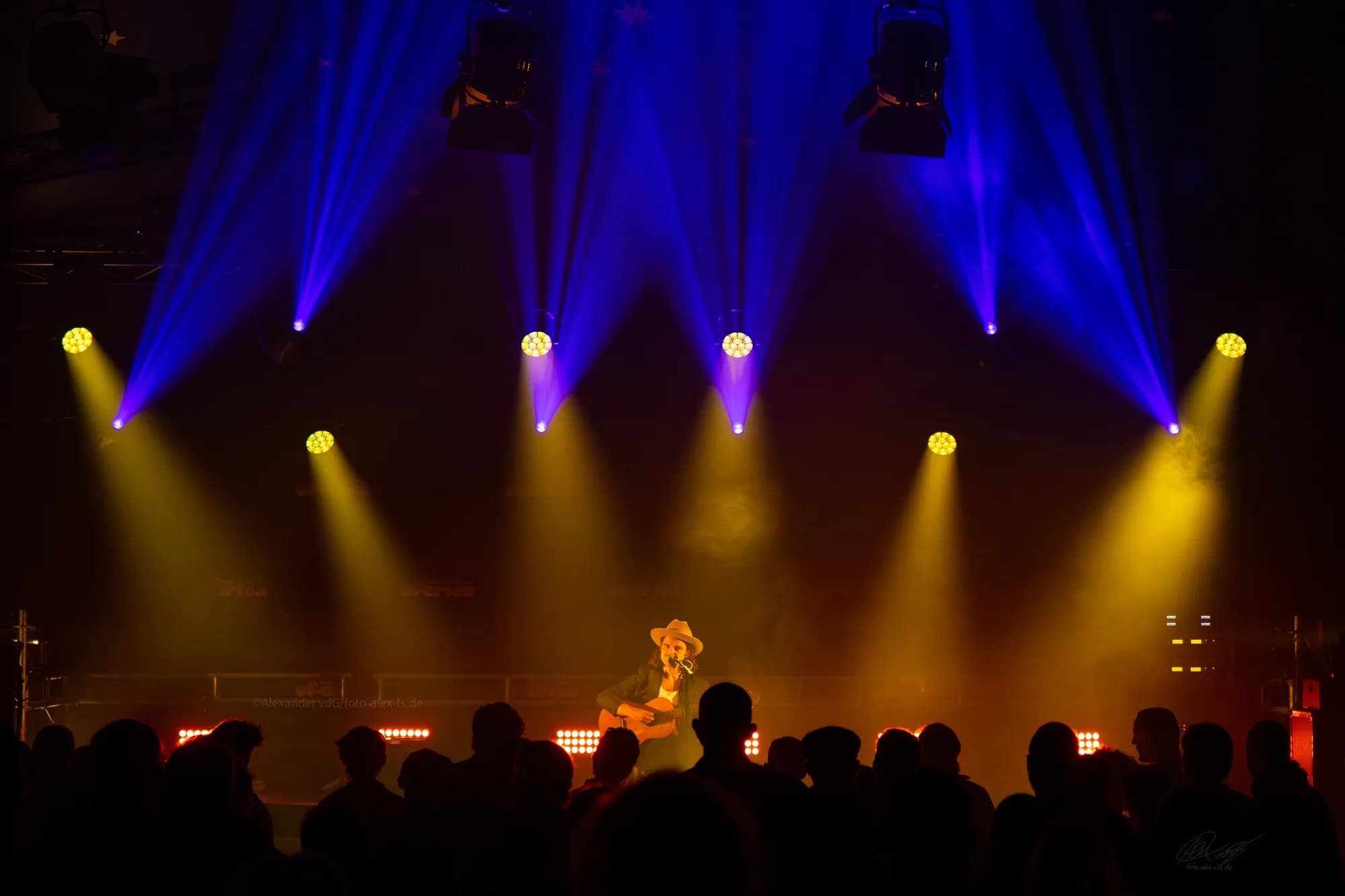 Smiling food vendors serving customers at their wooden festival stand.