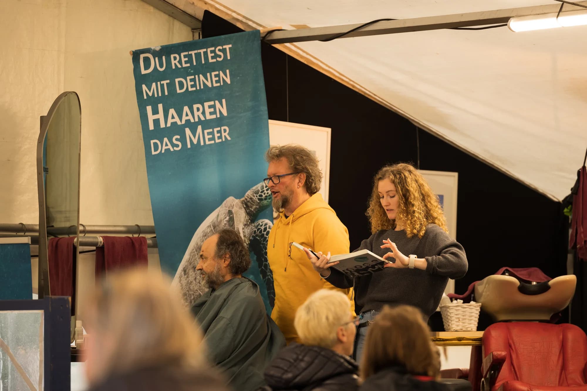 A sustainable hair styling workshop with a banner about saving the ocean with your hair.