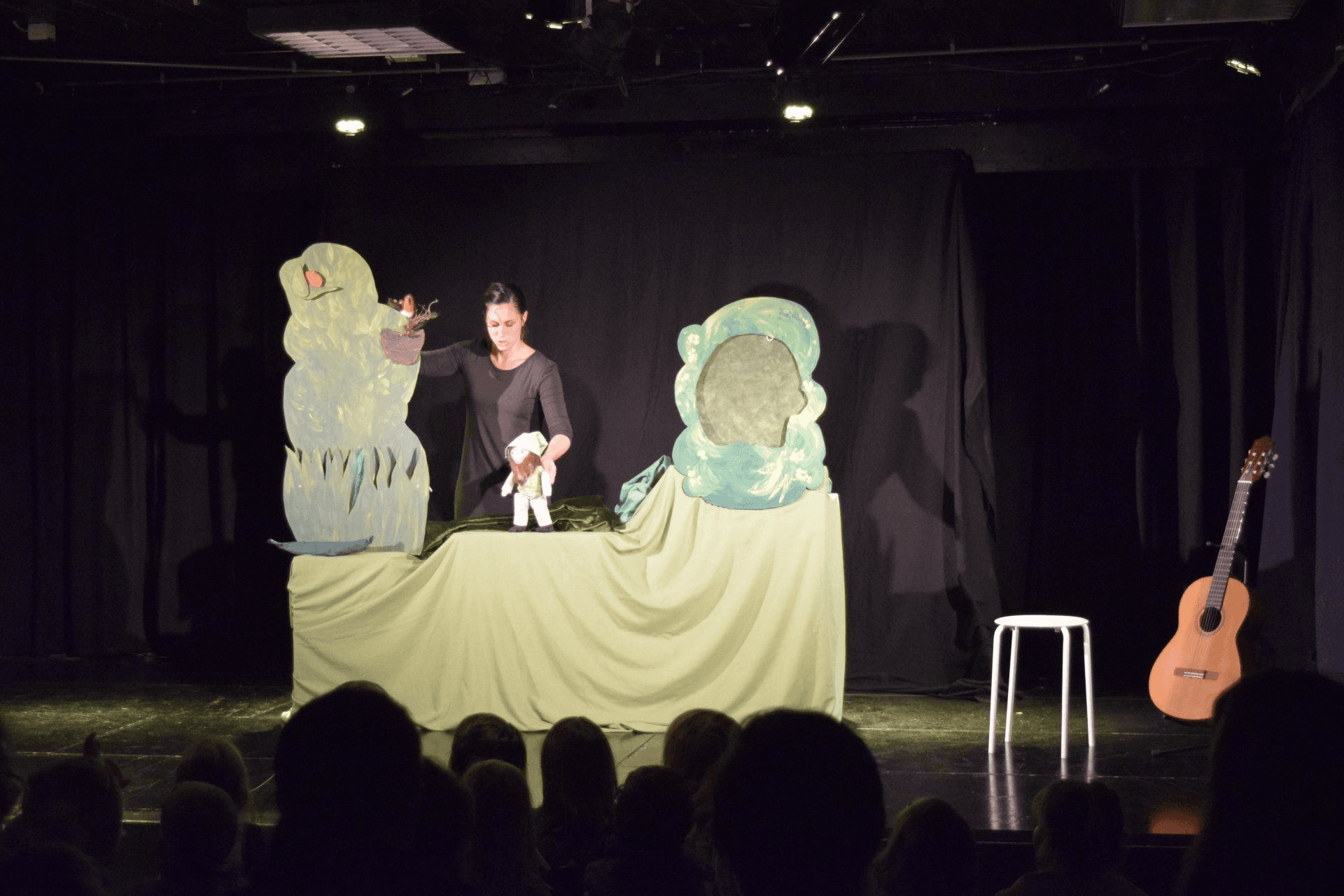 Kindertheater-Ensemble auf der Bühne mit Puppen und Musikinstrumenten