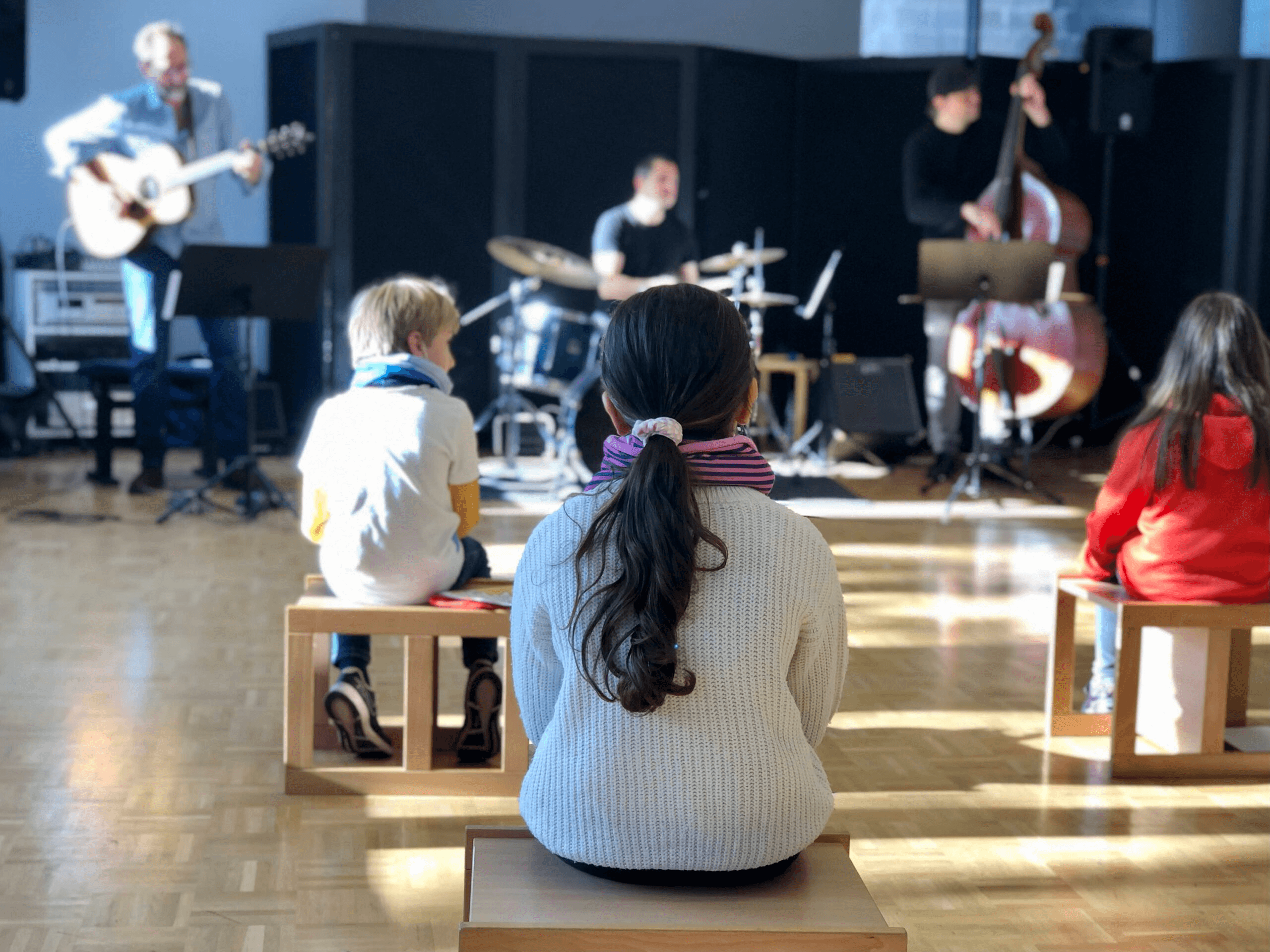 Johanna und Johannes auf der Buehne mit Instrumenten, umgeben von lachenden Kindern