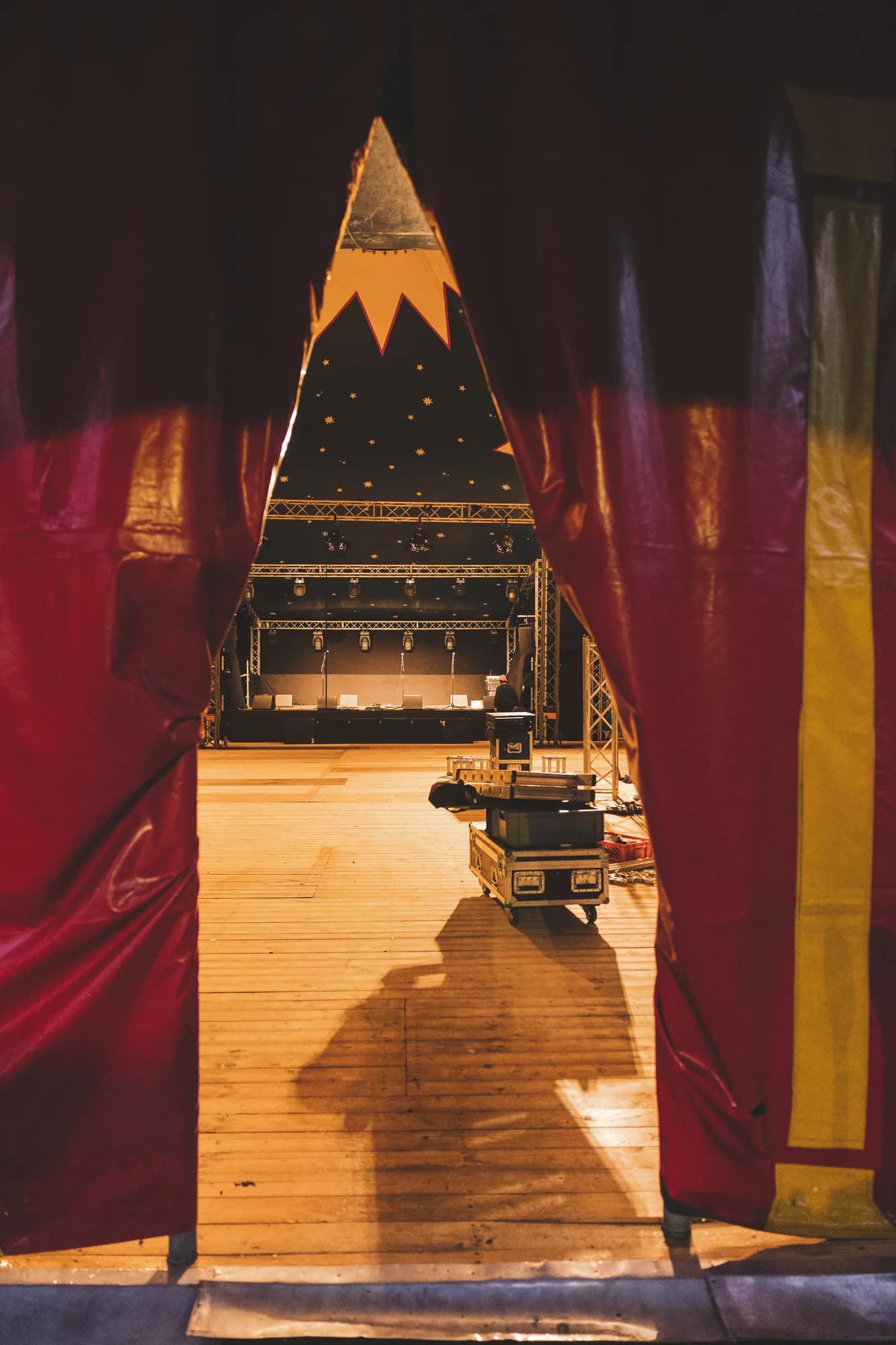 A view of the empty main stage through parted red curtains with a starry backdrop.