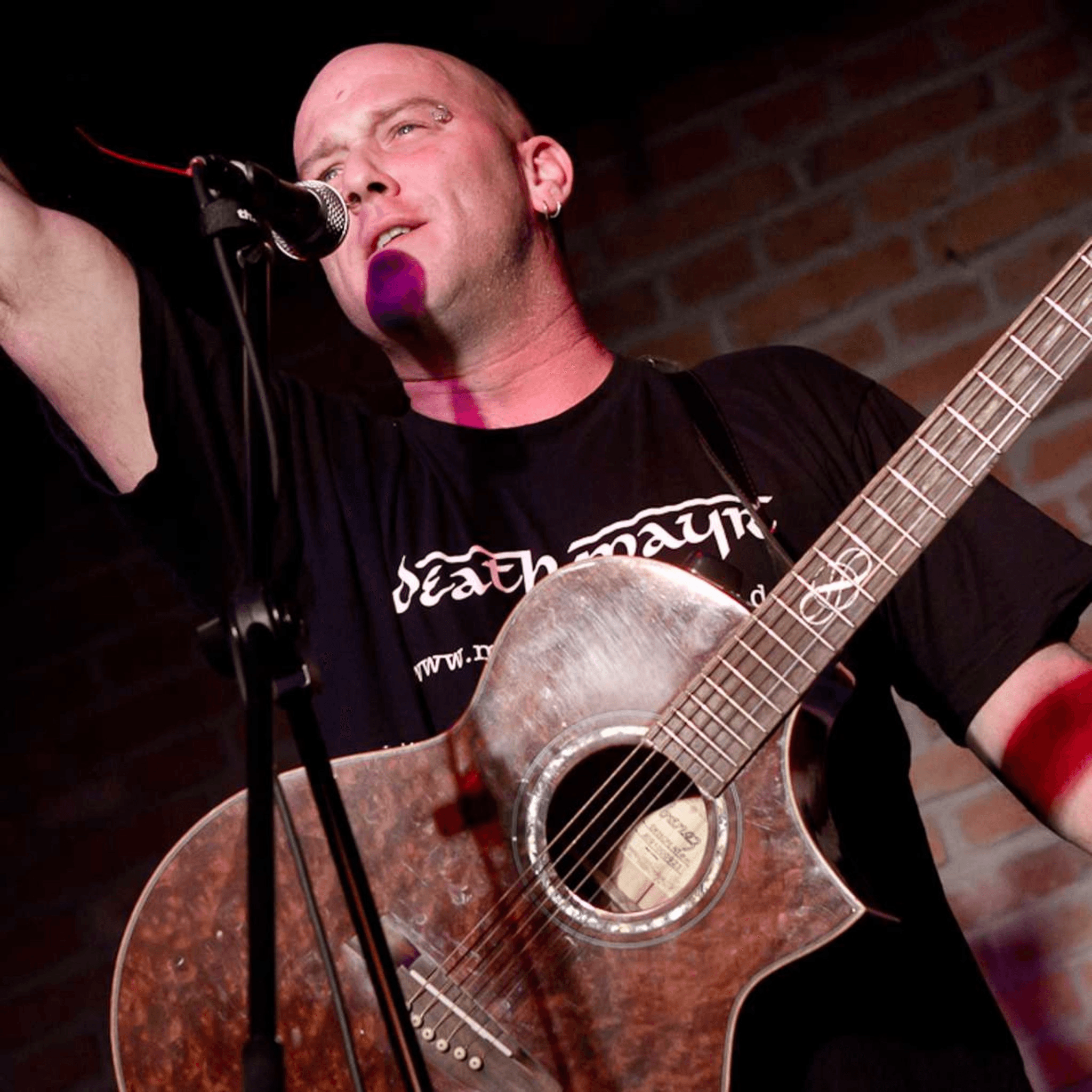 Michi Dietmayr auf der Bühne mit Gitarre, lachend