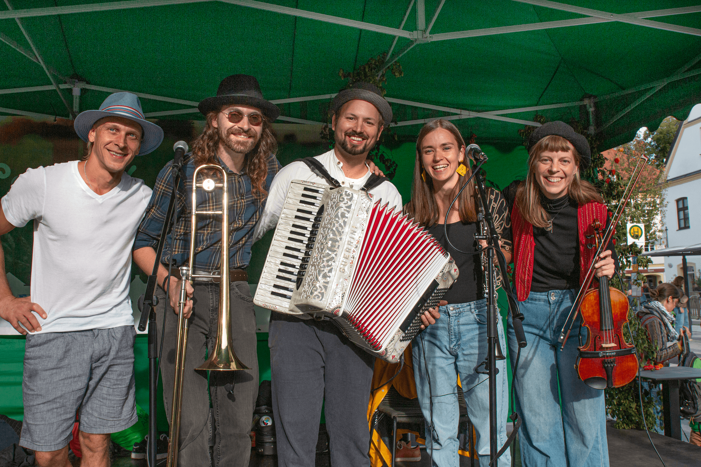 The band Chakulou performing live outdoors with accordion, violin, and trombone