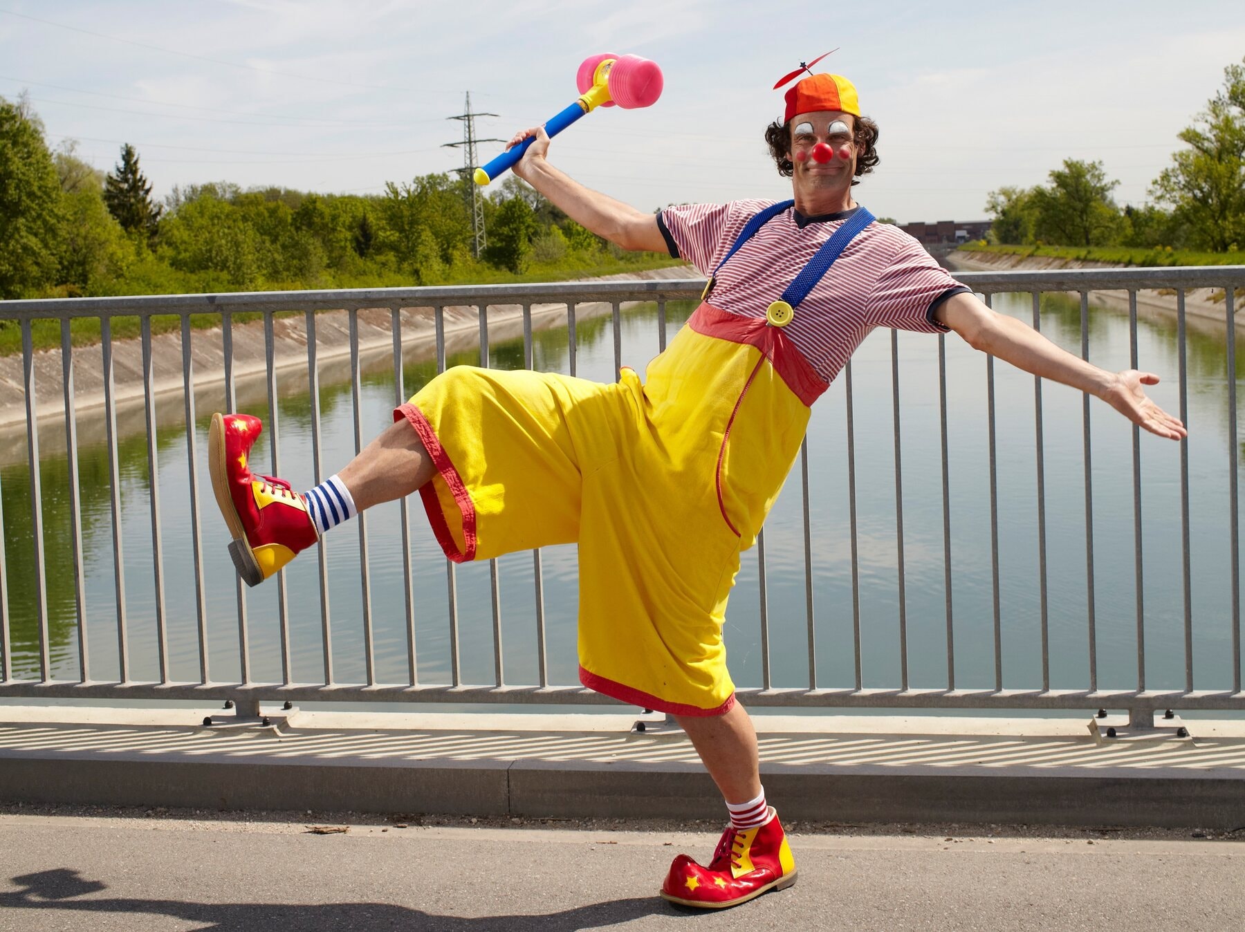Clown Toni Toss with red nose and yellow trousers by the water